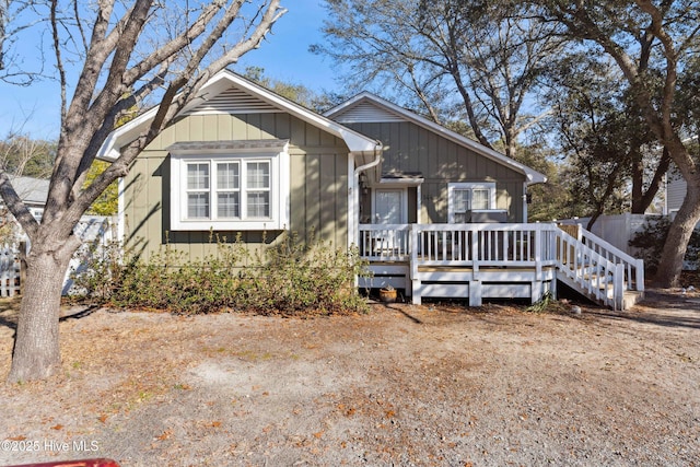 view of front of home with board and batten siding, fence, and a wooden deck