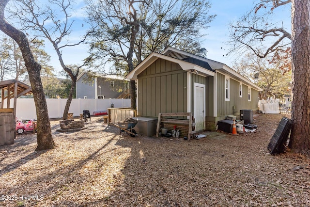 exterior space with an outdoor fire pit, a fenced backyard, and central air condition unit