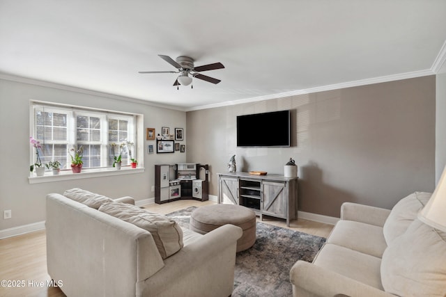 living area with light wood-style floors, ceiling fan, baseboards, and crown molding