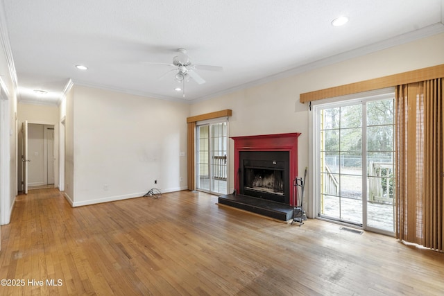 unfurnished living room with visible vents, baseboards, a fireplace with raised hearth, and wood finished floors