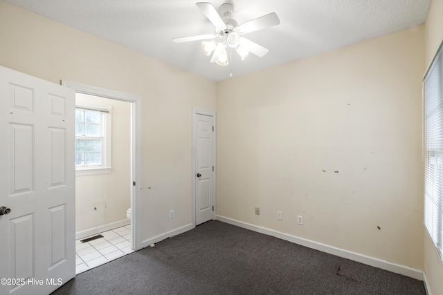 unfurnished bedroom with a textured ceiling, carpet floors, visible vents, and baseboards