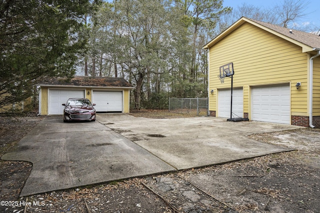 view of side of property with a garage, fence, and an outbuilding