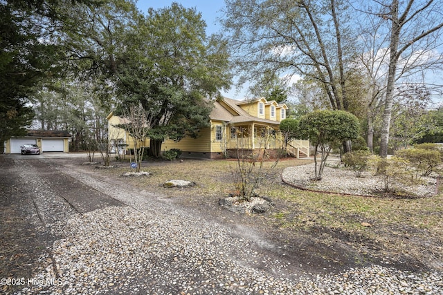 view of front facade with a porch, a garage, a shingled roof, an outdoor structure, and crawl space