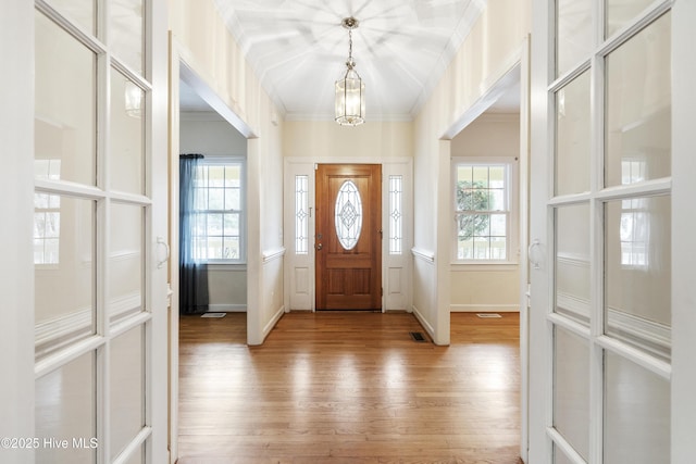 entrance foyer with ornamental molding, a wealth of natural light, visible vents, and light wood-style floors