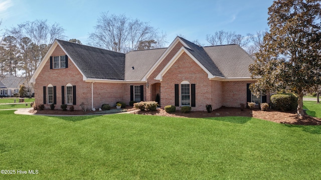 view of front of home with brick siding, a front lawn, and a shingled roof