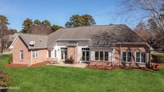 back of property with a patio area, a shingled roof, a lawn, and brick siding