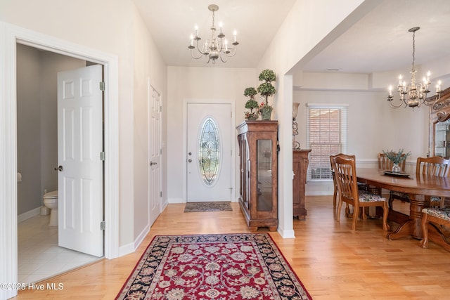 entrance foyer with baseboards, light wood finished floors, and a notable chandelier