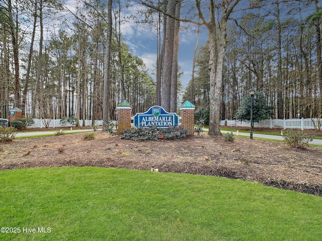 community sign with fence and a lawn