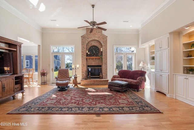 living area featuring light wood-type flooring, a brick fireplace, built in shelves, and a wealth of natural light