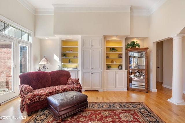 sitting room featuring decorative columns, a high ceiling, and crown molding