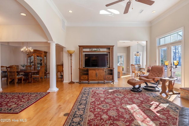 living area featuring arched walkways, light wood-style floors, decorative columns, and crown molding