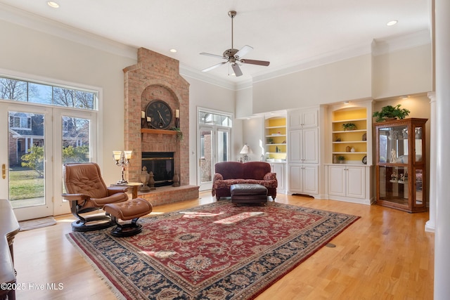 living room with crown molding, a fireplace, light wood-style flooring, and a high ceiling