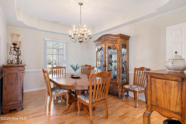 dining space with a notable chandelier, baseboards, light wood-type flooring, a tray ceiling, and crown molding