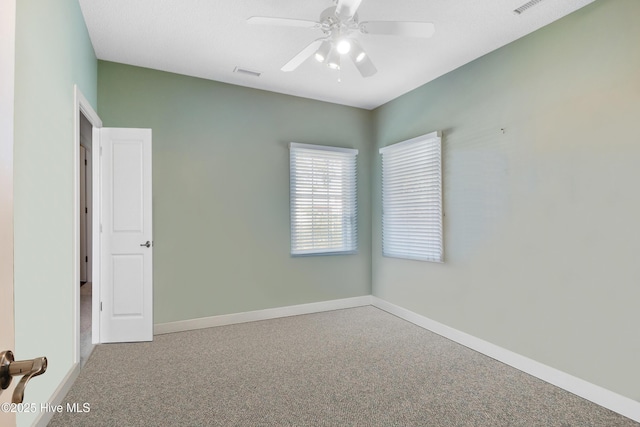 empty room featuring carpet, visible vents, ceiling fan, and baseboards