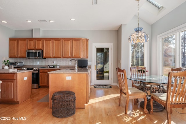 kitchen with tasteful backsplash, appliances with stainless steel finishes, a sink, and brown cabinets