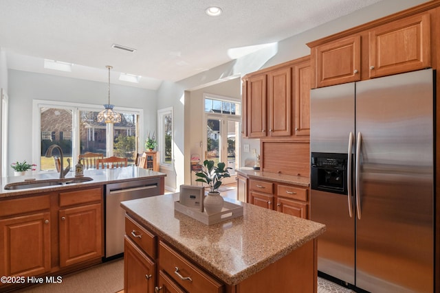 kitchen featuring appliances with stainless steel finishes, a sink, visible vents, and brown cabinets