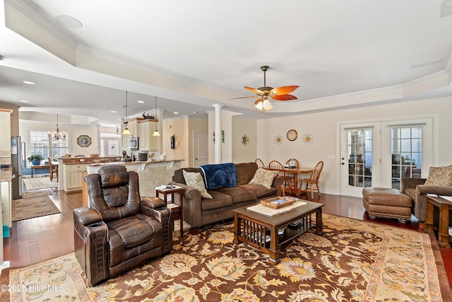 living area featuring ceiling fan with notable chandelier, a raised ceiling, crown molding, and hardwood / wood-style flooring