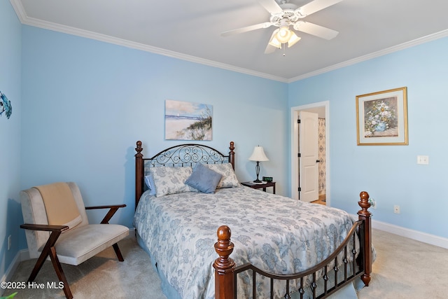 carpeted bedroom with ensuite bath, baseboards, ornamental molding, and ceiling fan