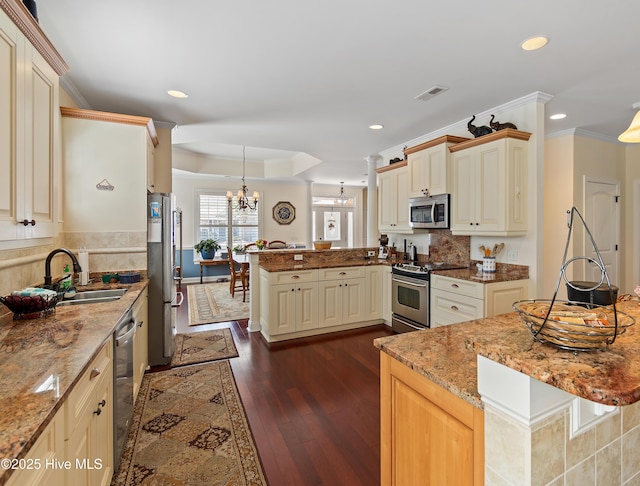 kitchen with visible vents, appliances with stainless steel finishes, a peninsula, a sink, and a notable chandelier