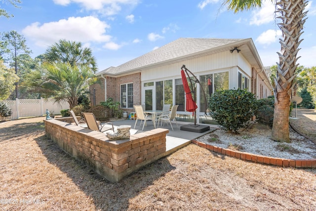 back of property featuring a patio area, fence, brick siding, and roof with shingles