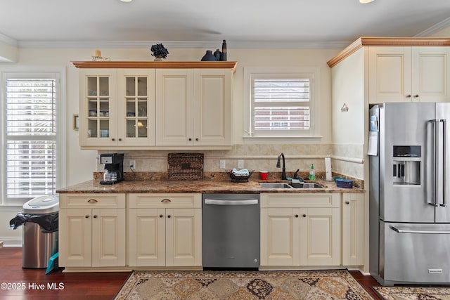 kitchen featuring appliances with stainless steel finishes, a healthy amount of sunlight, a sink, and crown molding