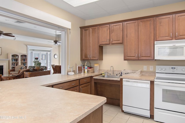 kitchen featuring white appliances, a fireplace, light countertops, and a sink