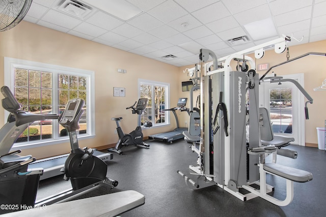 gym with visible vents, a paneled ceiling, and baseboards