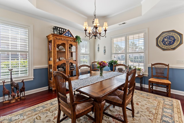 dining area with a wealth of natural light, a tray ceiling, wood finished floors, and visible vents