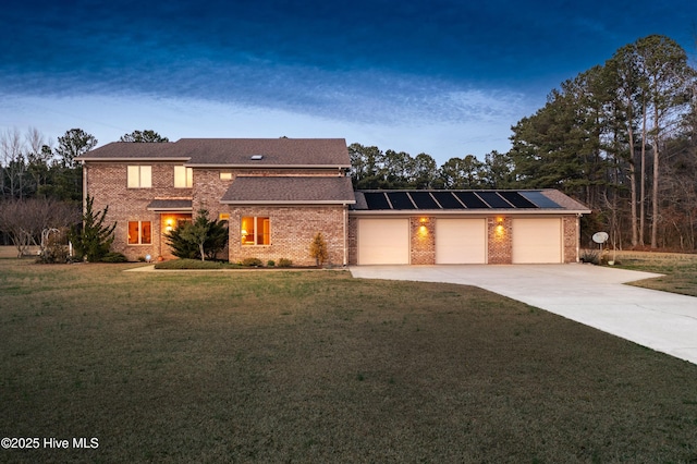 view of front of home with a garage, solar panels, brick siding, concrete driveway, and a front lawn