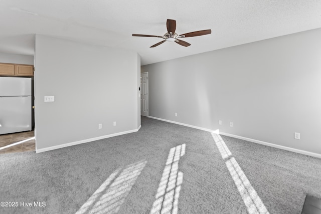 carpeted empty room featuring ceiling fan, a textured ceiling, and baseboards