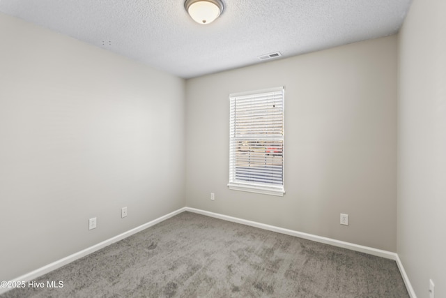 unfurnished room featuring carpet, visible vents, baseboards, and a textured ceiling