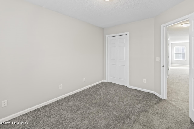 unfurnished bedroom featuring a textured ceiling, carpet floors, a closet, and baseboards