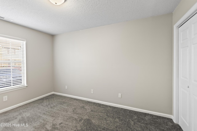 unfurnished bedroom featuring carpet, a textured ceiling, visible vents, and a closet