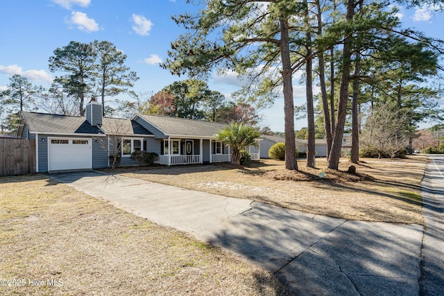 ranch-style home featuring a porch, an attached garage, fence, driveway, and a chimney