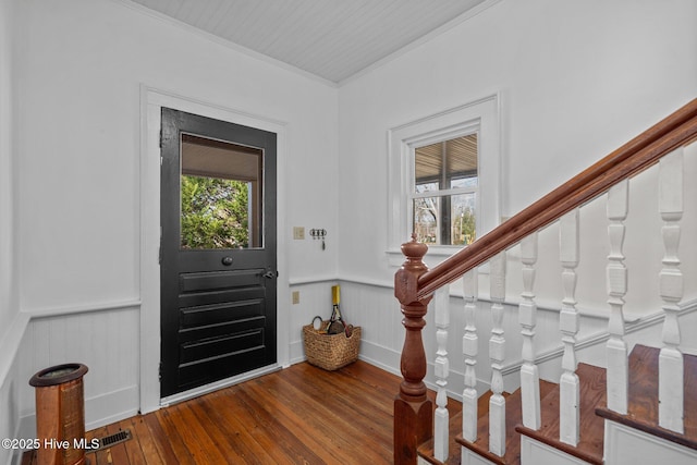 entryway with healthy amount of natural light, hardwood / wood-style floors, crown molding, and wainscoting