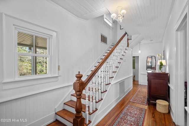 staircase with a chandelier, hardwood / wood-style flooring, and a wainscoted wall
