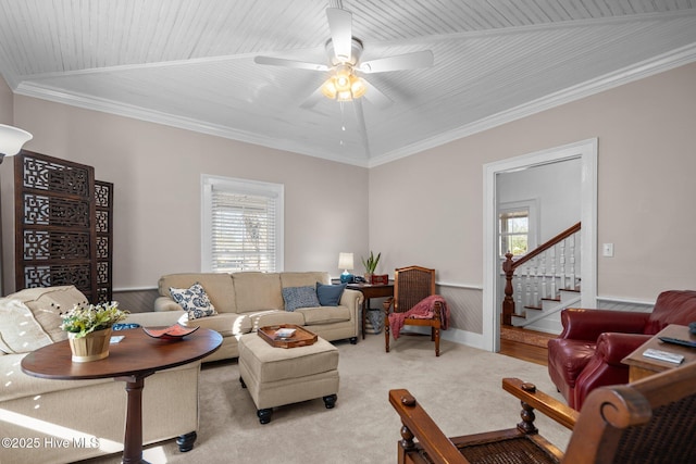 carpeted living area with stairway, ceiling fan, ornamental molding, and baseboards
