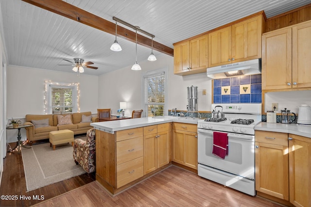 kitchen featuring white gas range oven, under cabinet range hood, a peninsula, light wood-style floors, and beamed ceiling