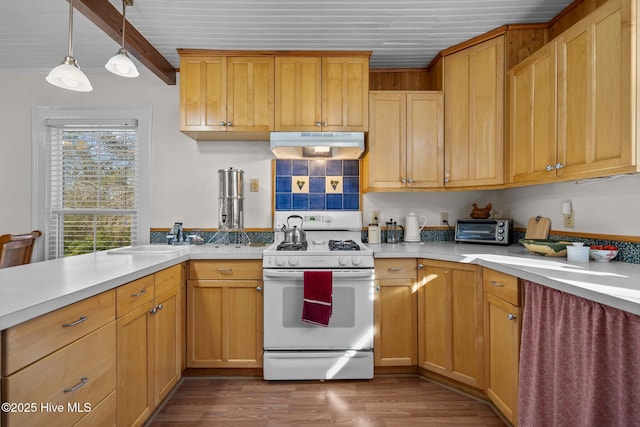 kitchen with white range with gas cooktop, under cabinet range hood, a sink, light countertops, and dark wood-type flooring