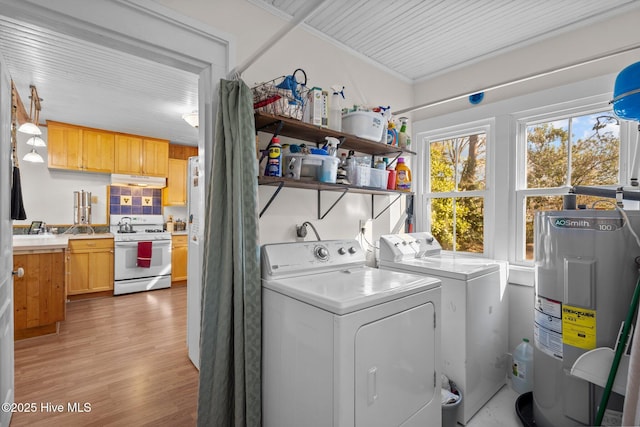 laundry room with electric water heater, independent washer and dryer, crown molding, and light wood-type flooring