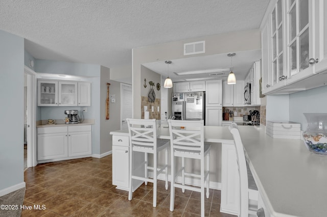 kitchen featuring visible vents, appliances with stainless steel finishes, glass insert cabinets, and white cabinets