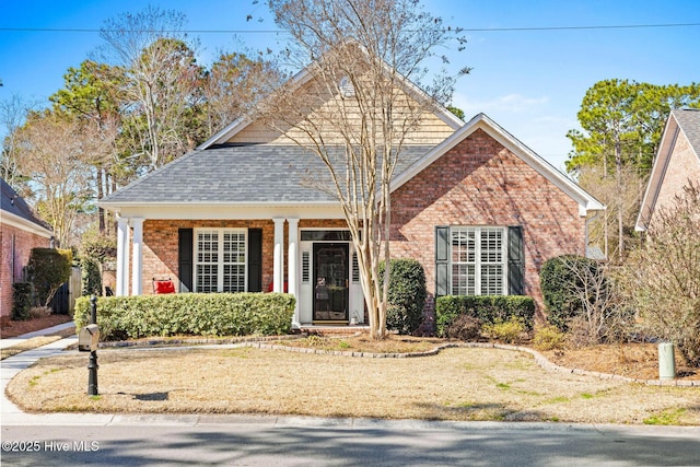 view of front facade with brick siding and roof with shingles