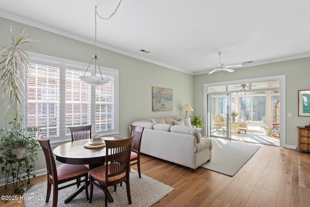 dining space featuring wood-type flooring, visible vents, baseboards, and ornamental molding