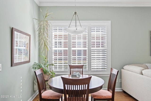 dining area featuring baseboards, wood finished floors, and crown molding