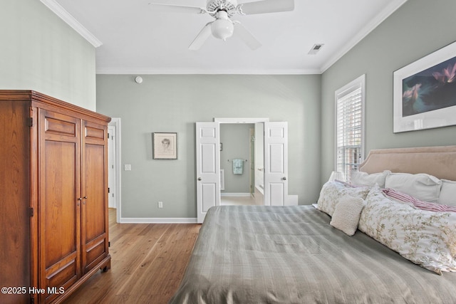 bedroom with visible vents, baseboards, a ceiling fan, wood finished floors, and crown molding