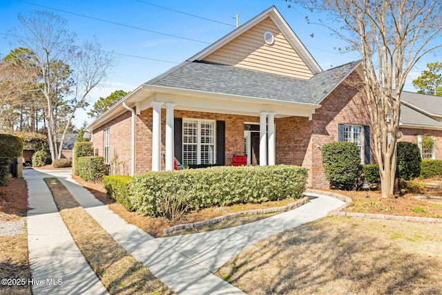 view of front of house featuring brick siding and roof with shingles