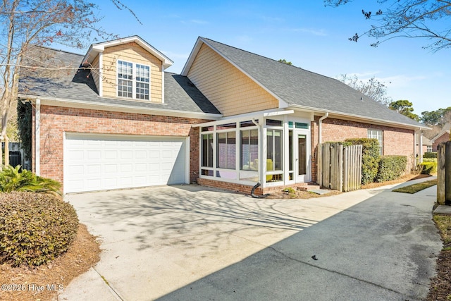 view of front of home featuring a garage, driveway, brick siding, and a sunroom