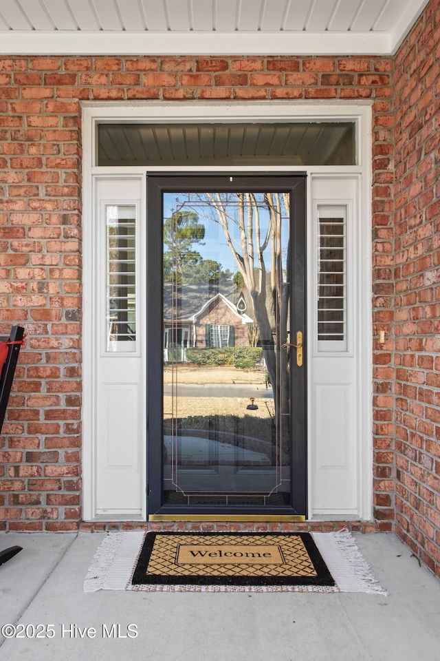 doorway to property featuring brick siding