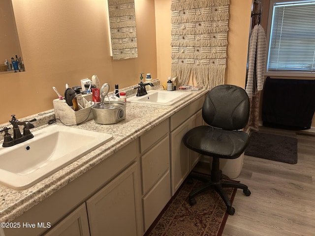 bathroom featuring double vanity, a sink, and wood finished floors