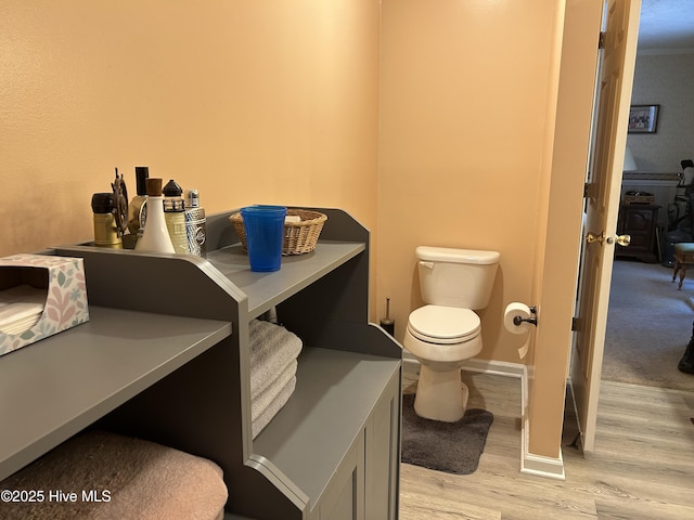 bathroom featuring toilet, baseboards, and wood finished floors